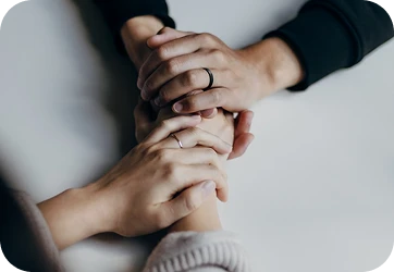 Two hands clasped over another pair of hands on a table