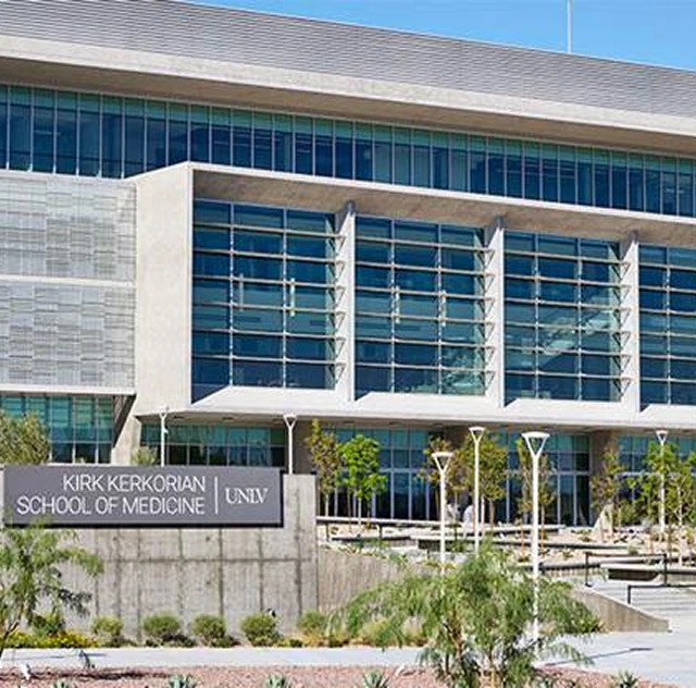 Modern building facade with large windows and planting in front. Sign reads "School of Medicine."